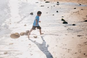 dziecko biega za piłką plażową dmuchaną